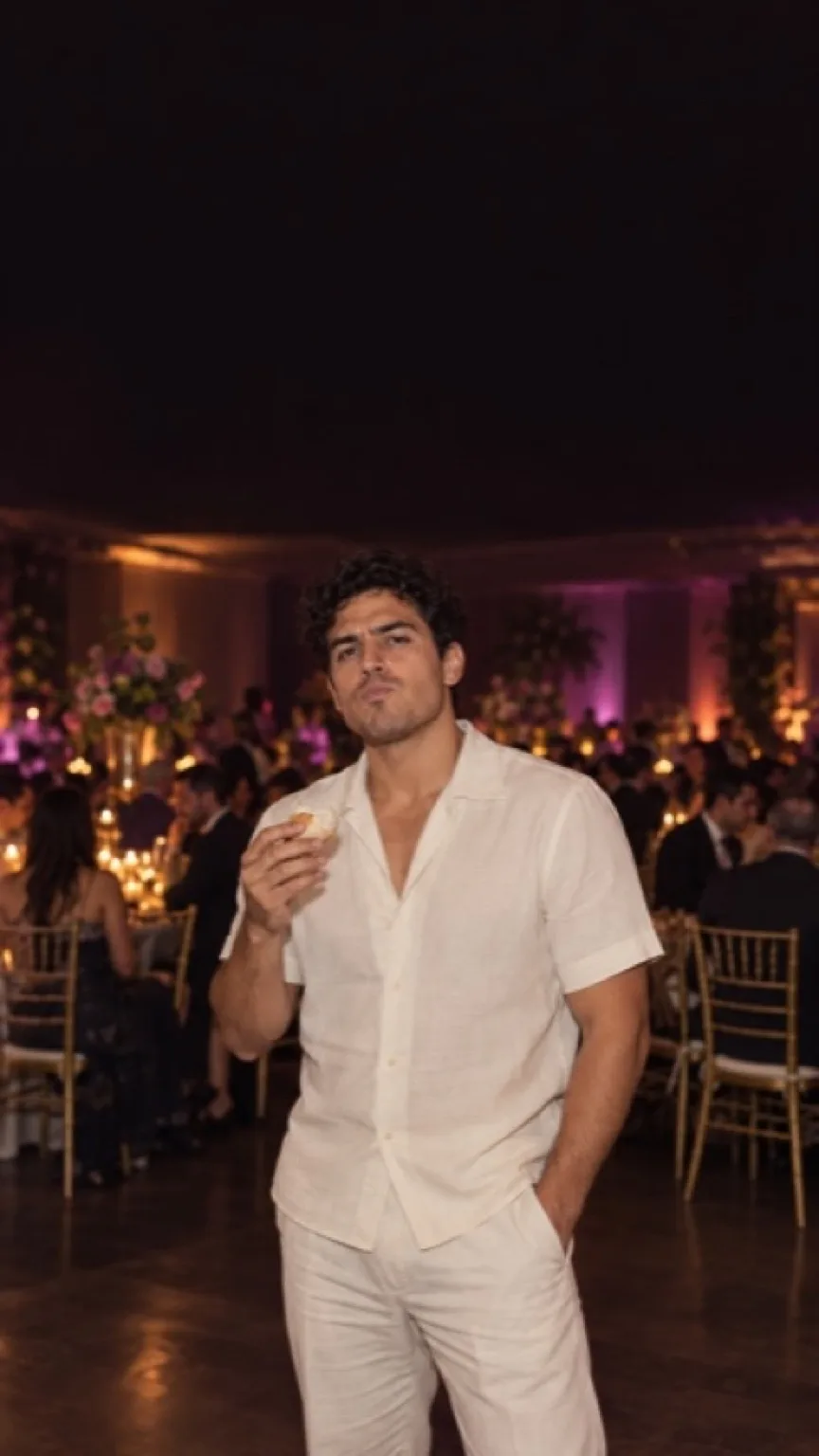 A party guest steps out of the crowd and stares into the camera at a quinceañera.